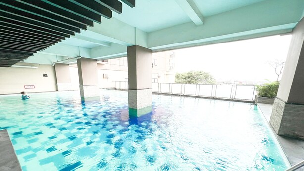 Une piscine intérieure à l’eau claire, dotée d’un sol carrelé et d’un plafond au design à lattes.