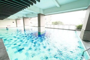 Ein überdachter Pool mit klarem Wasser, Fliesenboden und einer Decke mit Lamellenstruktur.