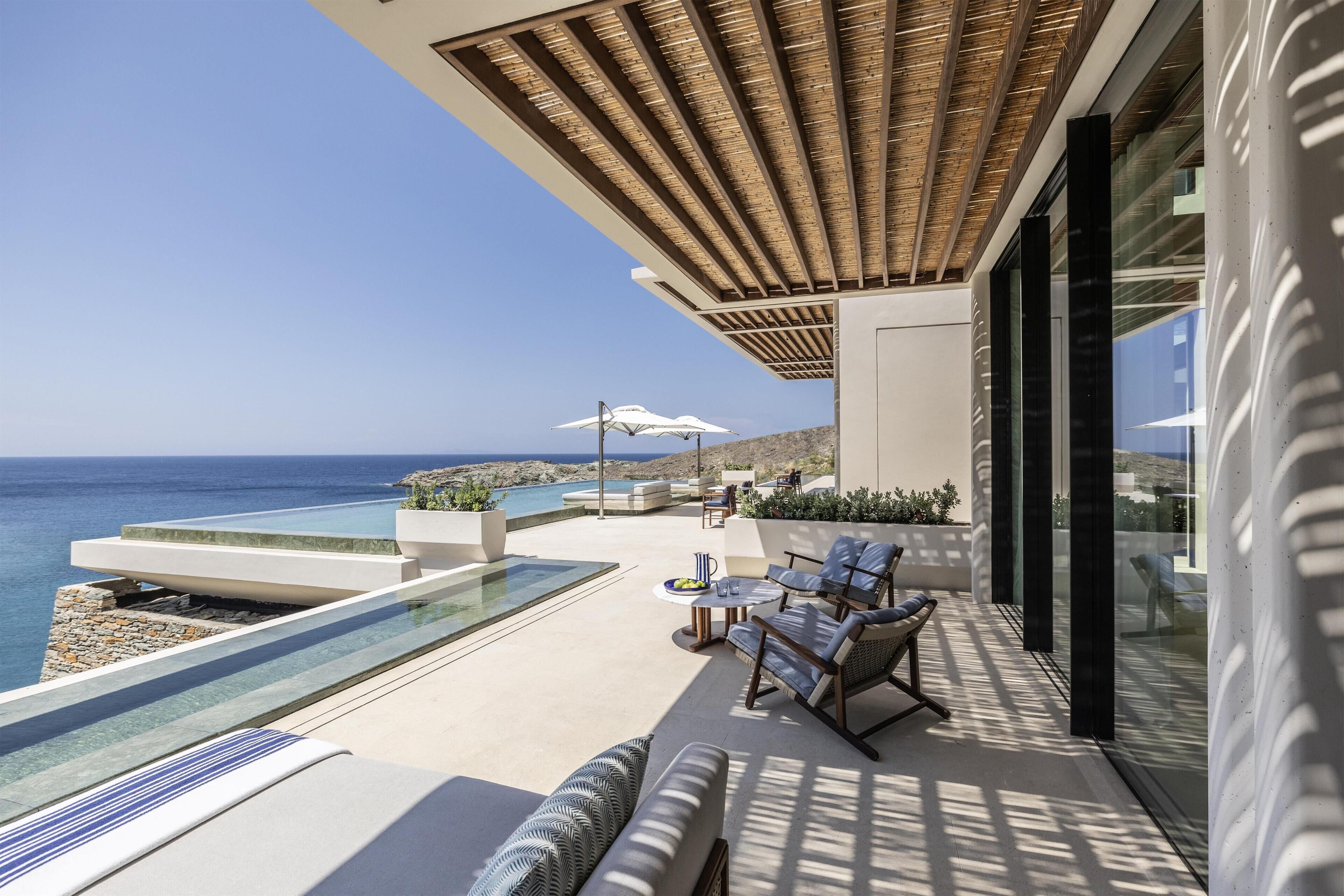 A modern outdoor terrace with a pool, seating, and a view of the sea.
