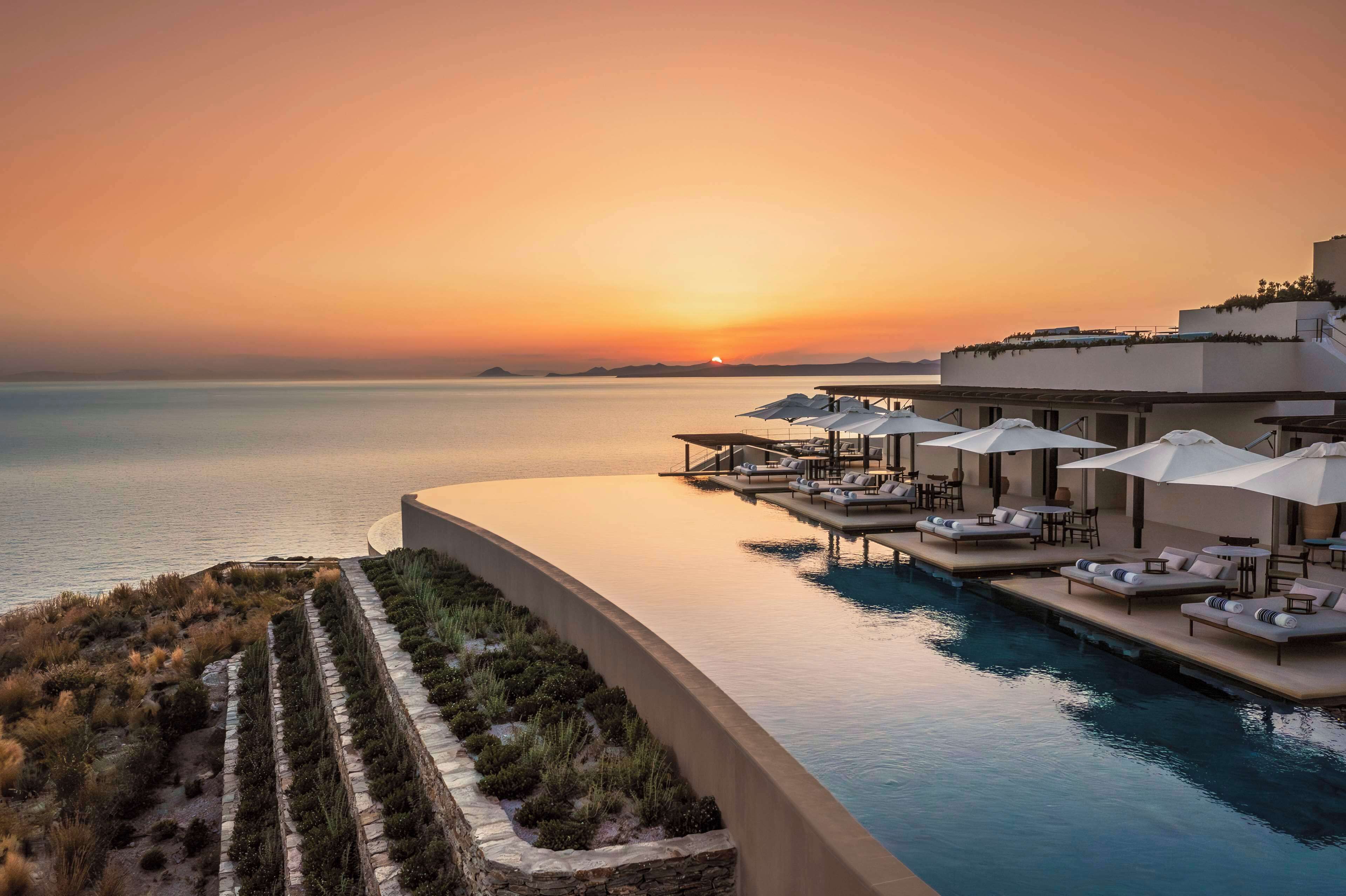 Un resort con piscina, sillas de descanso y sombrillas.