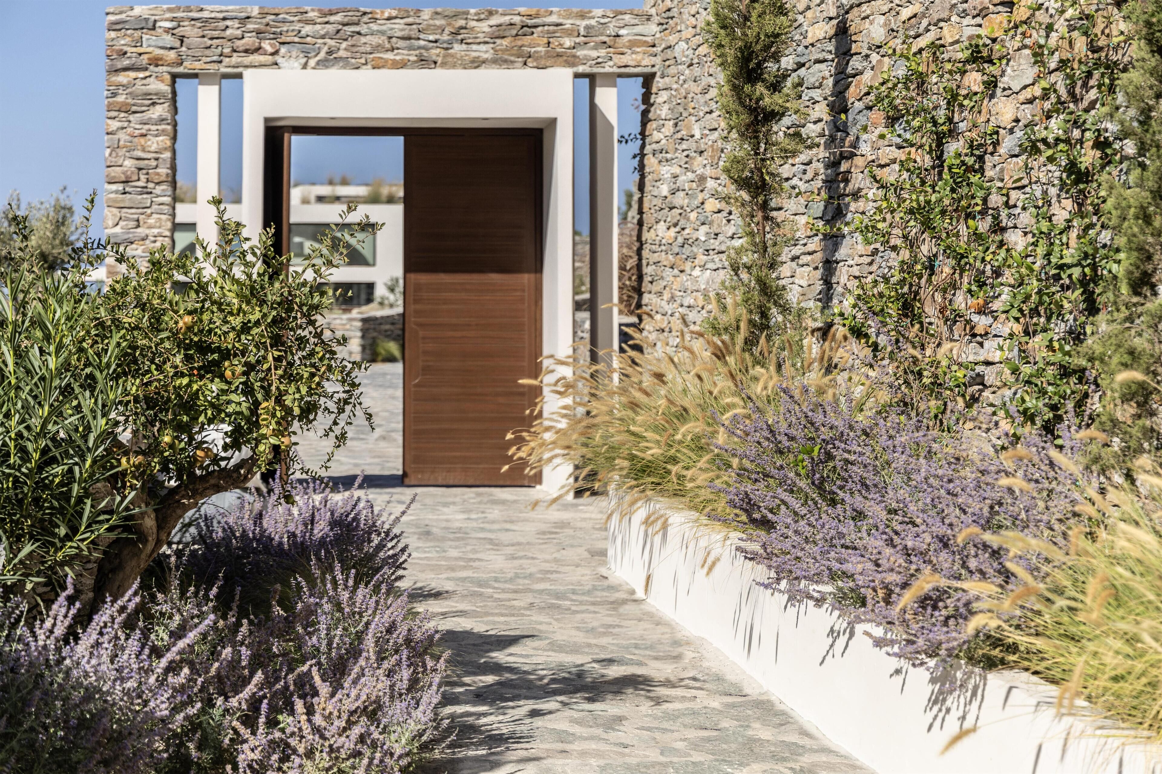 A modern building with a stone facade, a wooden door, and a pathway leading to it.