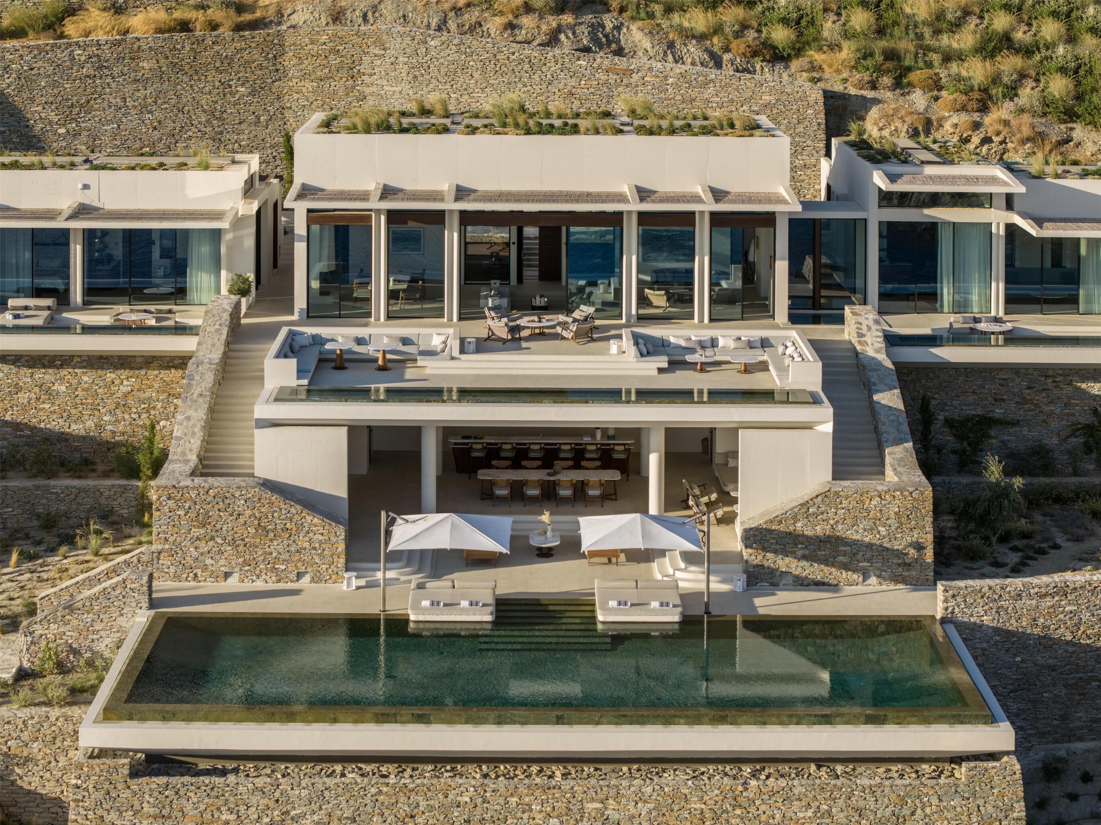 Un resort moderno con piscina en la azotea, mobiliario exterior y un muro de contención de piedra.