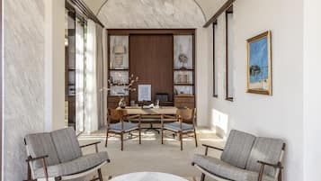 A modern interior with a marble wall, a wooden desk, two upholstered chairs, and a round coffee table.