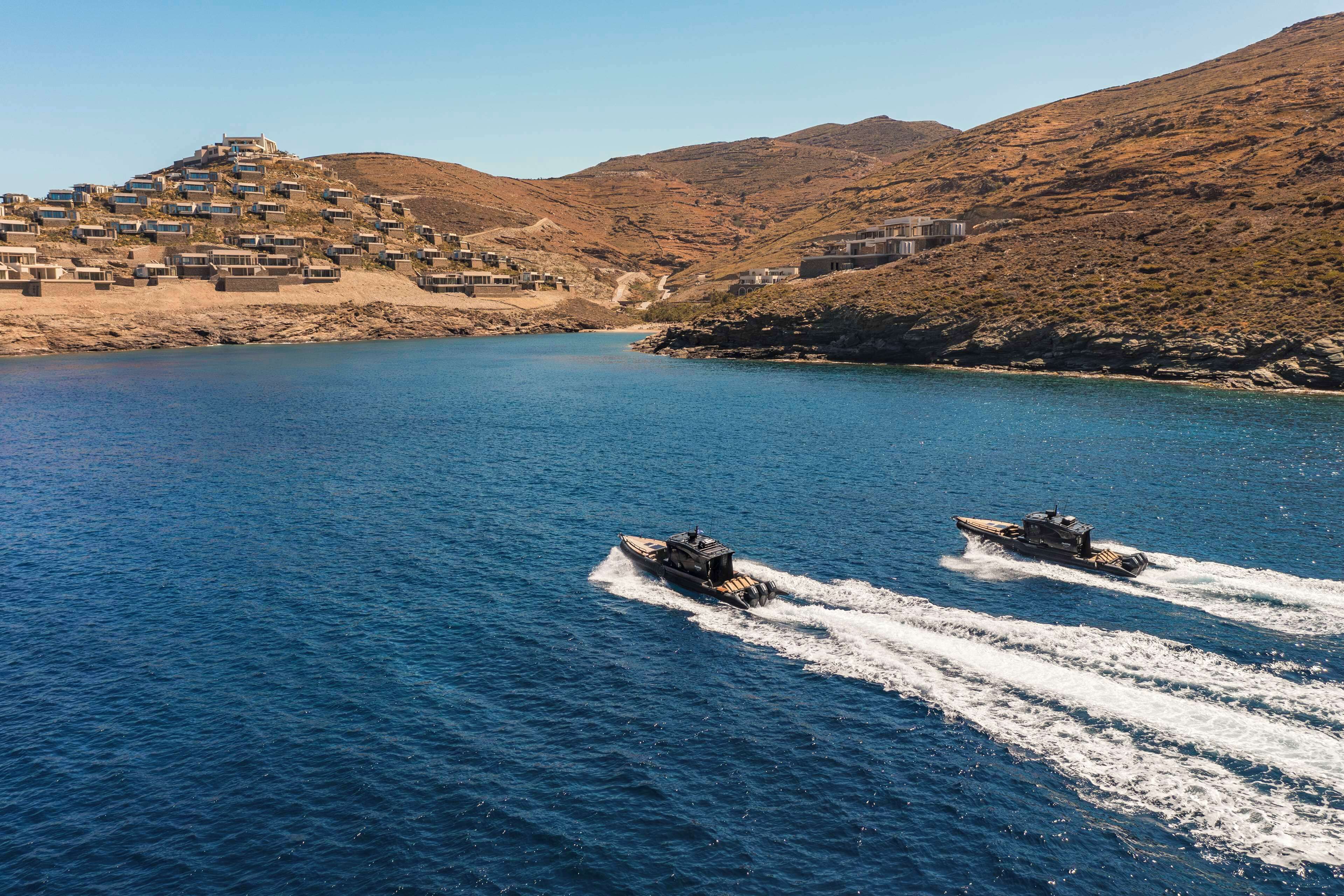 A coastal area with buildings on a hillside and two boats on the water.