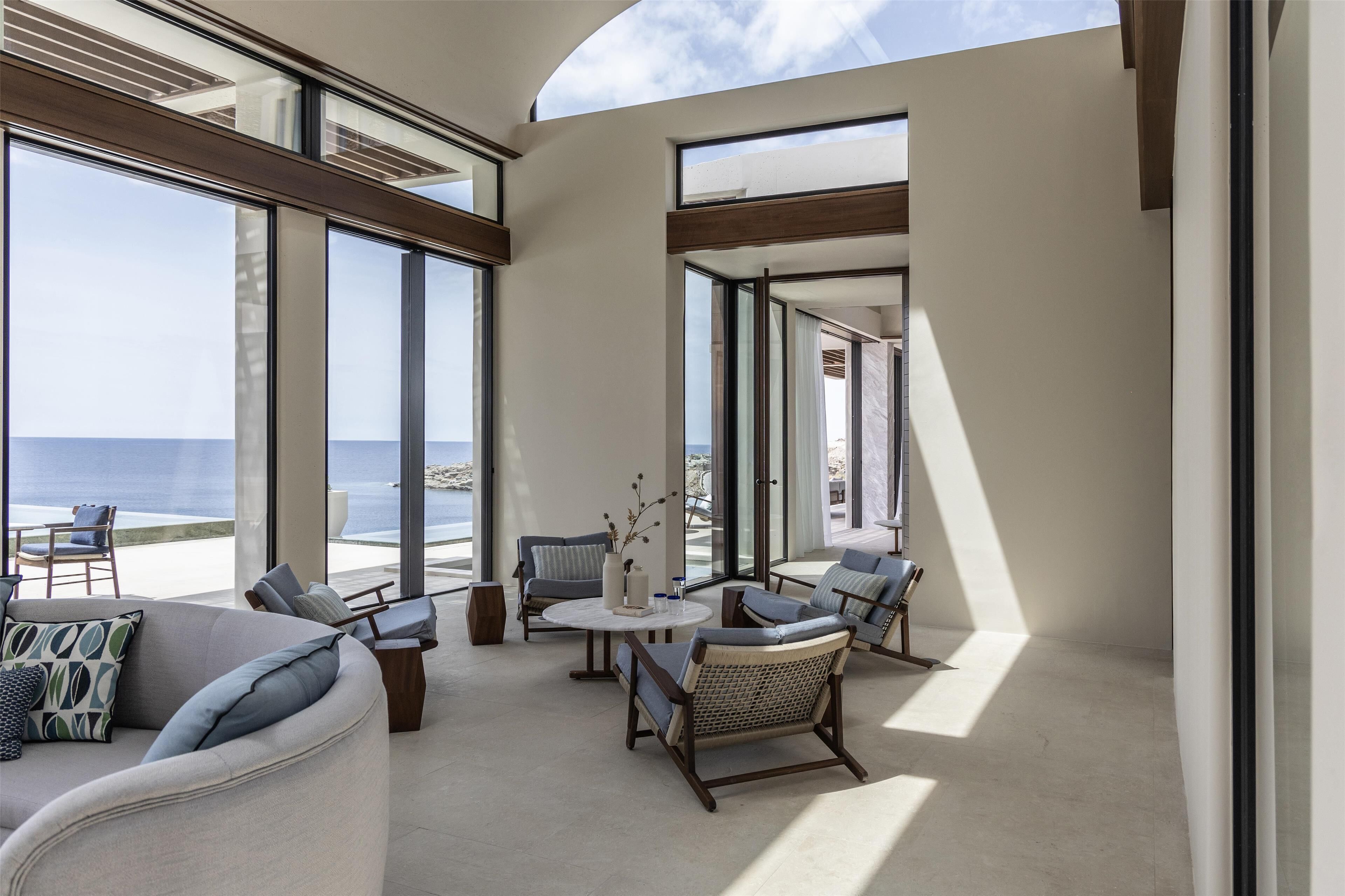 Un grand balcon offrant une vue sur la mer, aménagé avec un canapé, des fauteuils et une table.