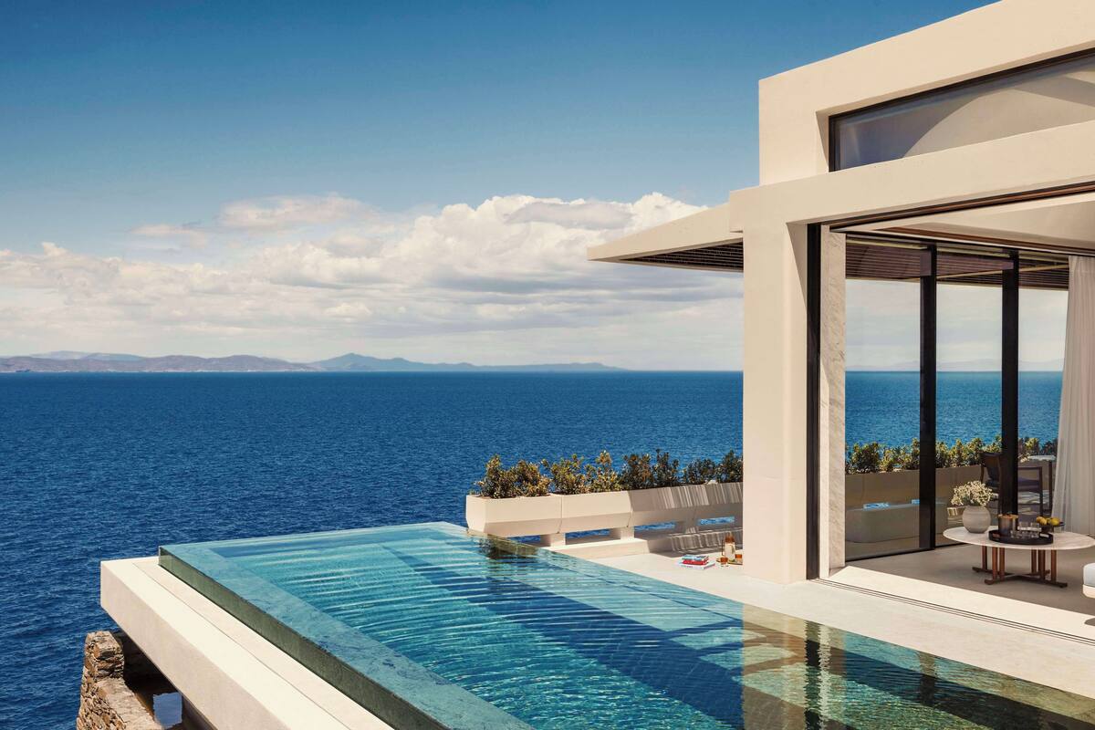 A modern infinity pool with a clear view of the sea and distant mountains.