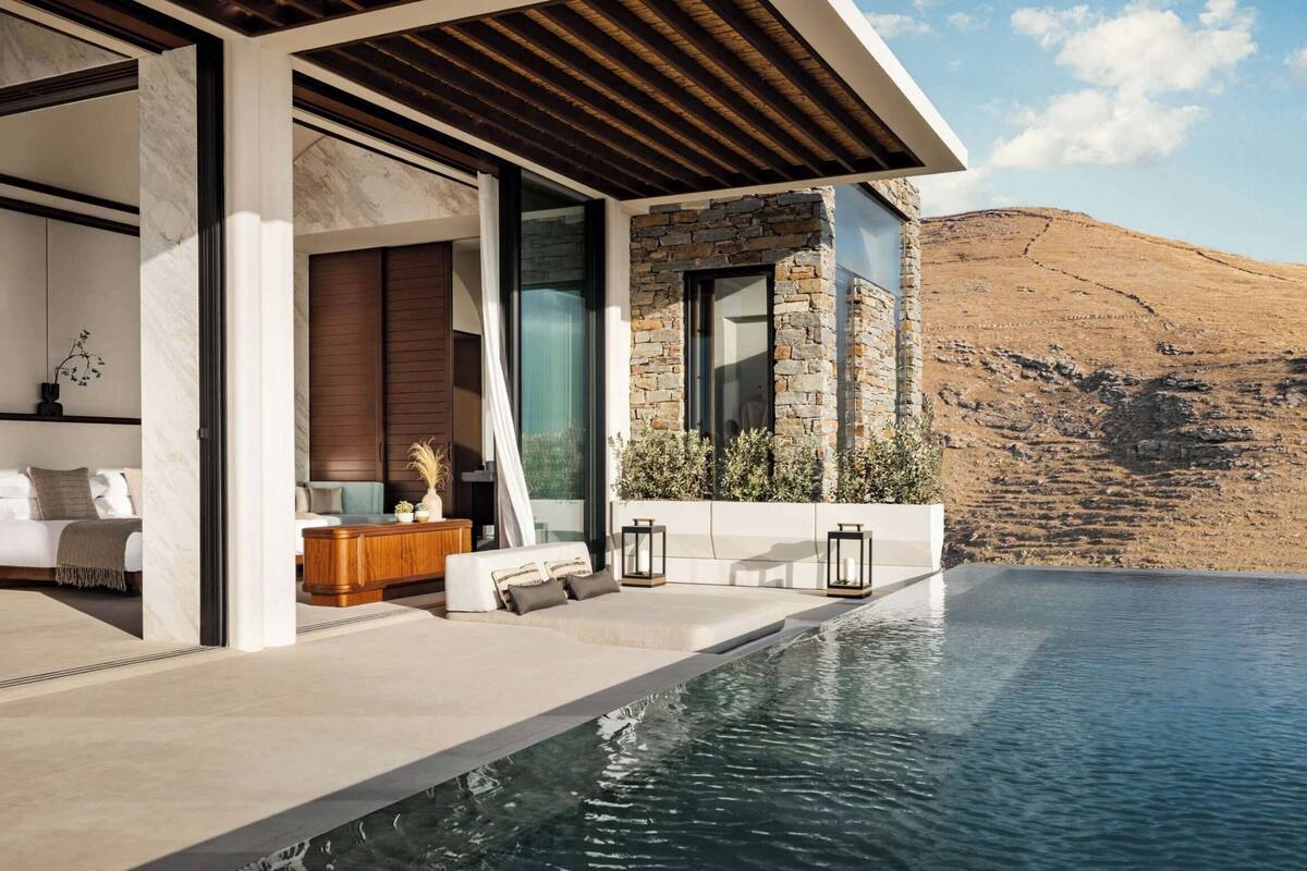 A modern outdoor pool area with a stone wall and a view of a dry landscape.