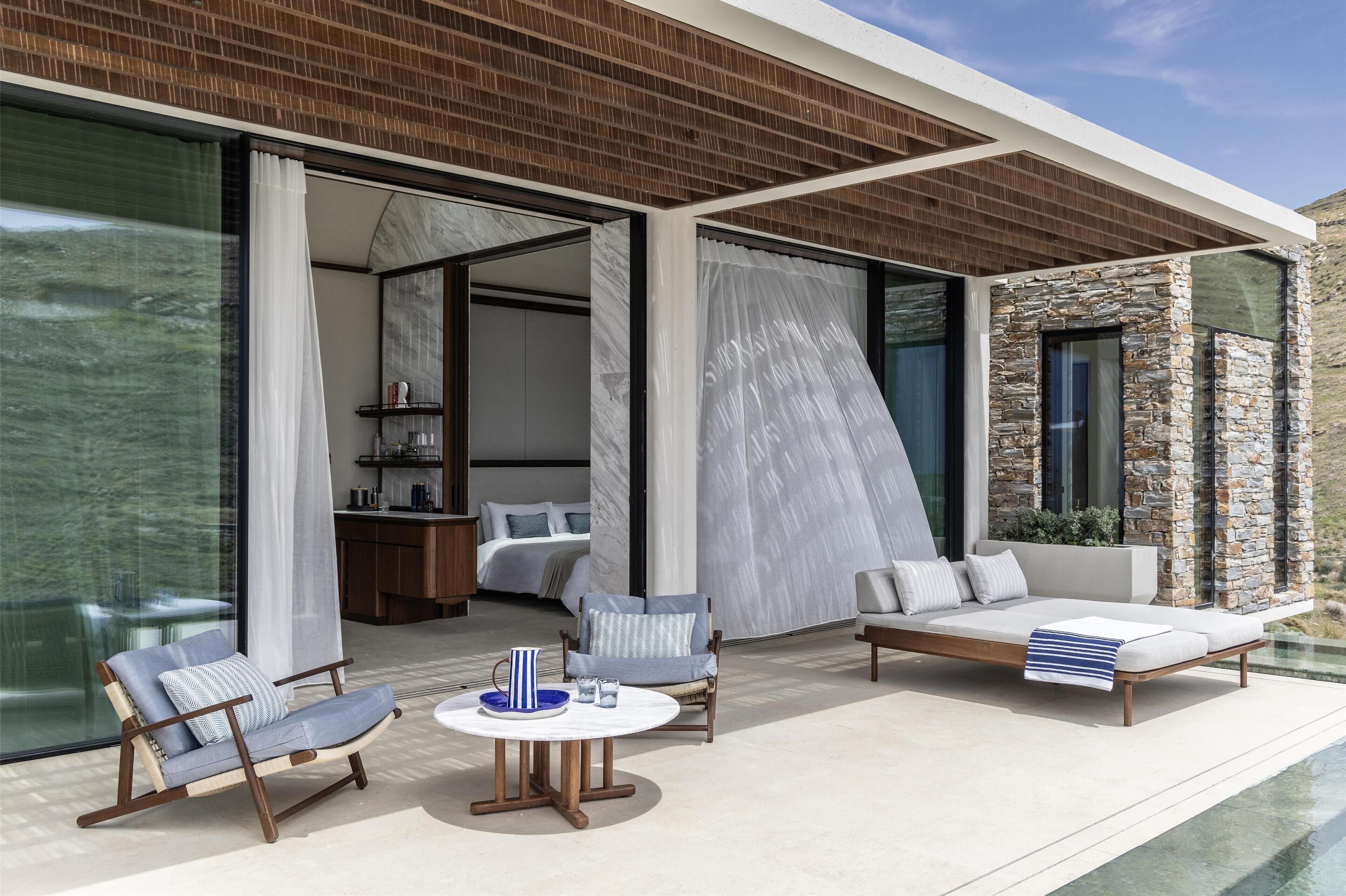A modern outdoor living space with a pool, seating areas, and a bedroom visible through large glass doors.