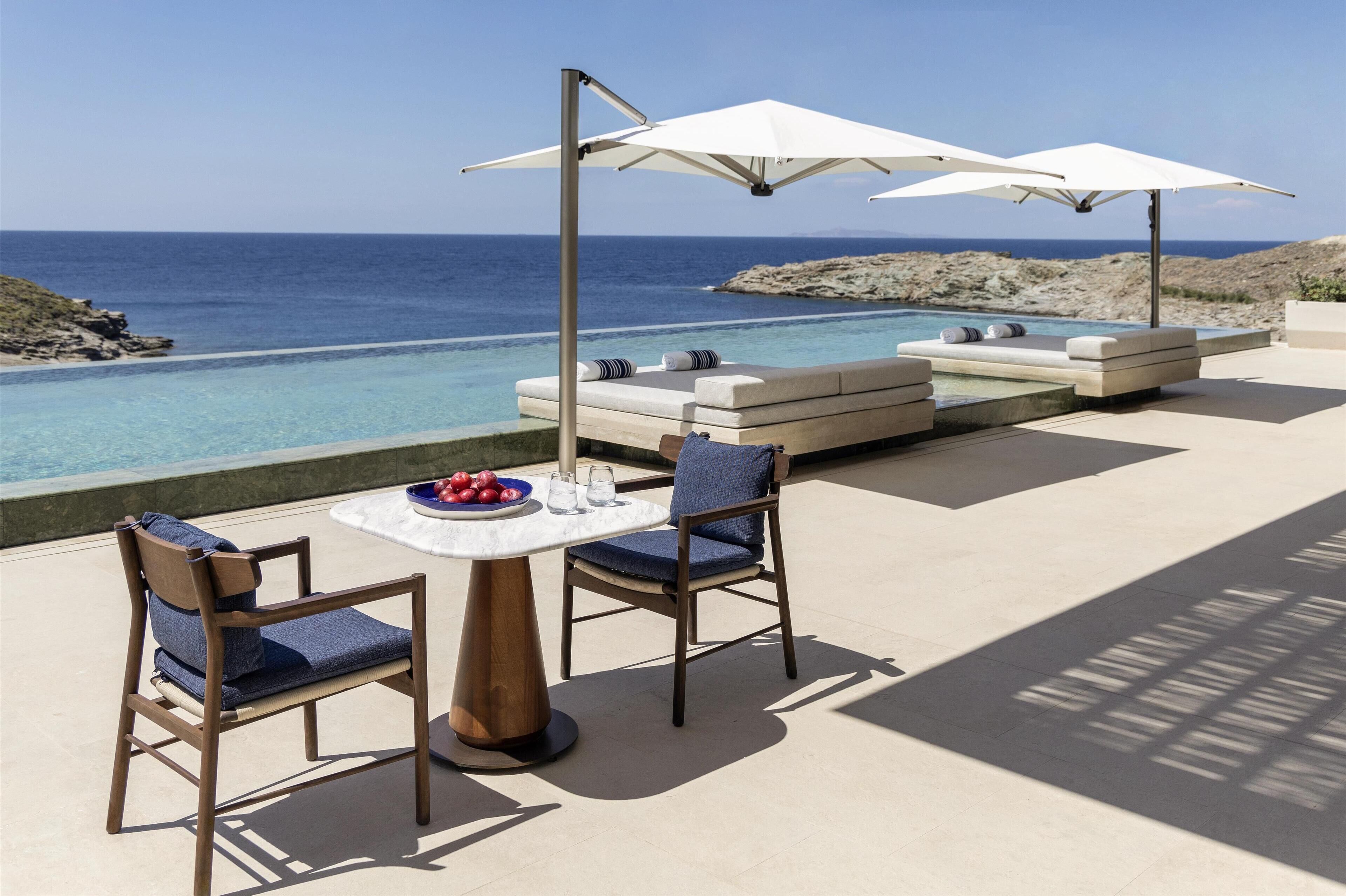 A poolside area with lounge chairs, a table with fruit, and umbrellas.