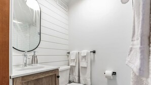 Een badkamer met een witte wastafel, een spiegel, een toilet en een handdoekhouder.