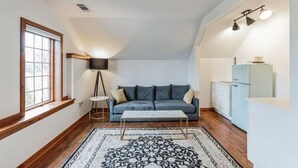 A cozy living room with a blue sofa, a coffee table, a patterned rug, and a small side table. - Thornton Studio w/ Kitchenette (Thornton)