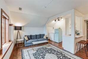Cozy living space with a loft-style ceiling, sofa, and kitchenette.