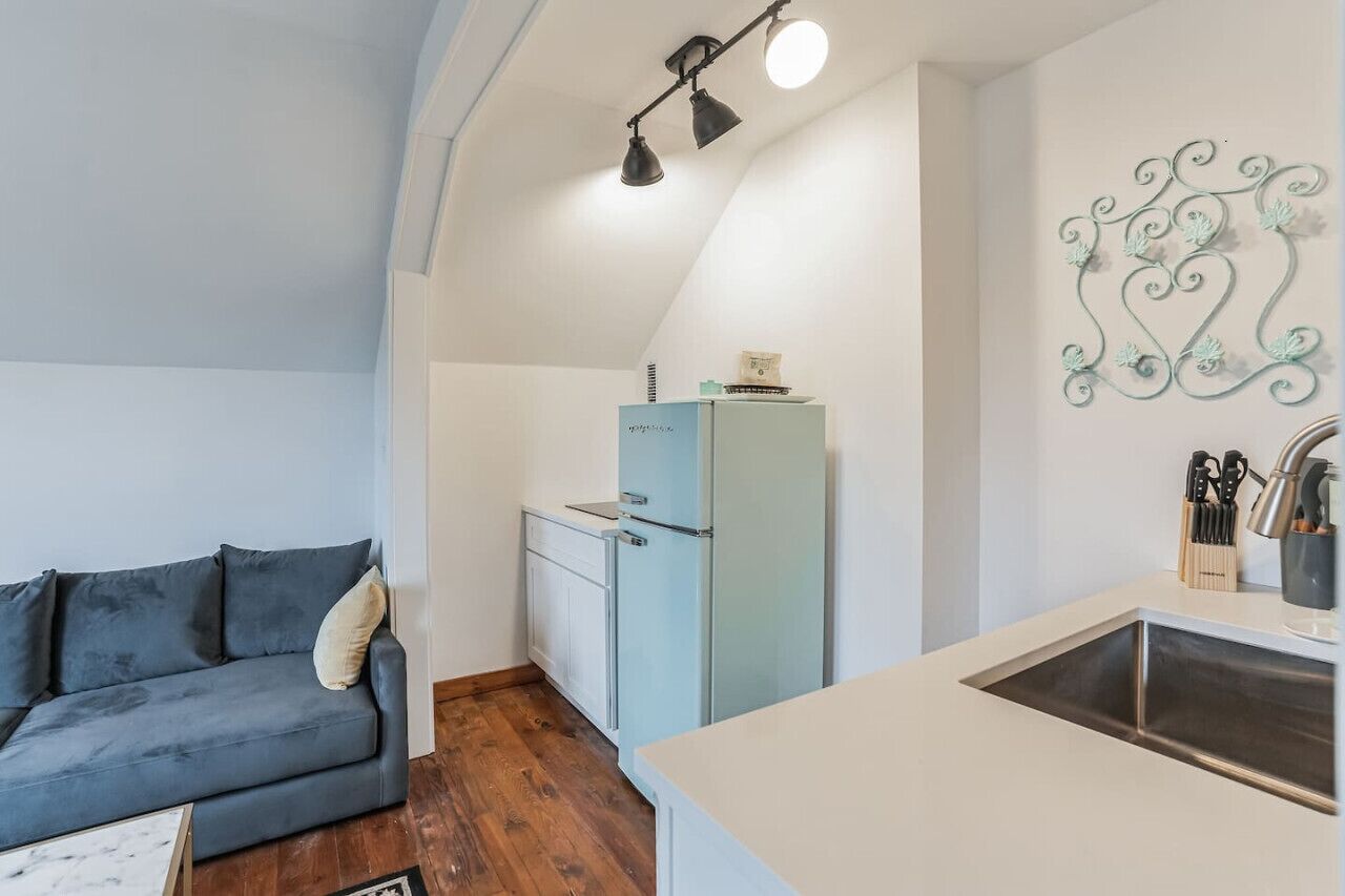 A compact living space with a sofa, a small kitchenette, and a decorative wall piece.