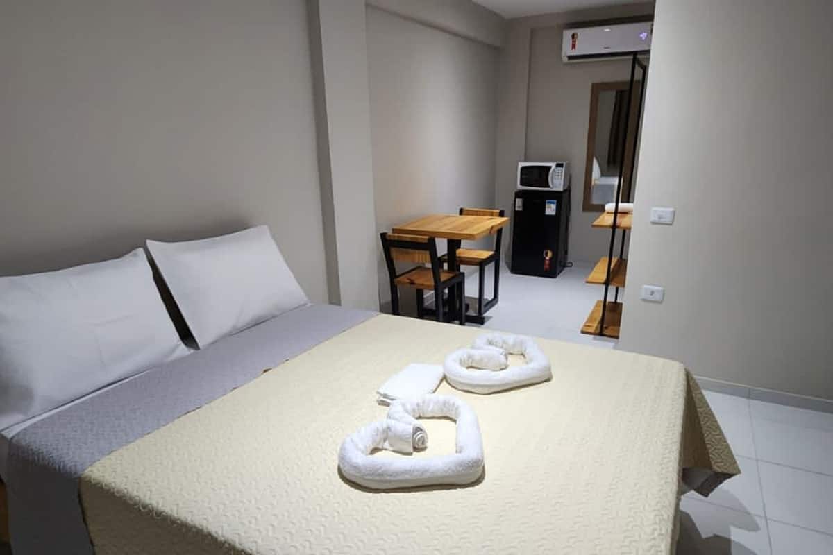 A hotel room with a bed, a desk, and a microwave.