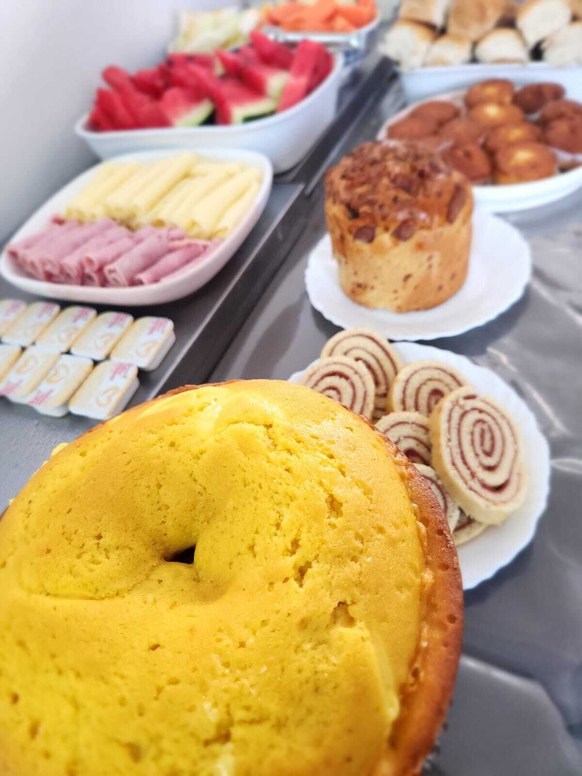 Un bufé de desayuno con diversas opciones de comida, incluyendo un pastel amarillo, bollería y fruta.