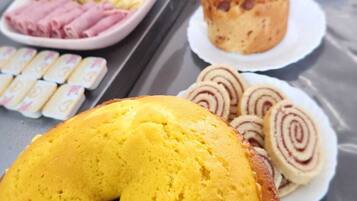 Un bufé de desayuno con diversas opciones de comida, incluyendo un pastel amarillo, bollería y fruta.