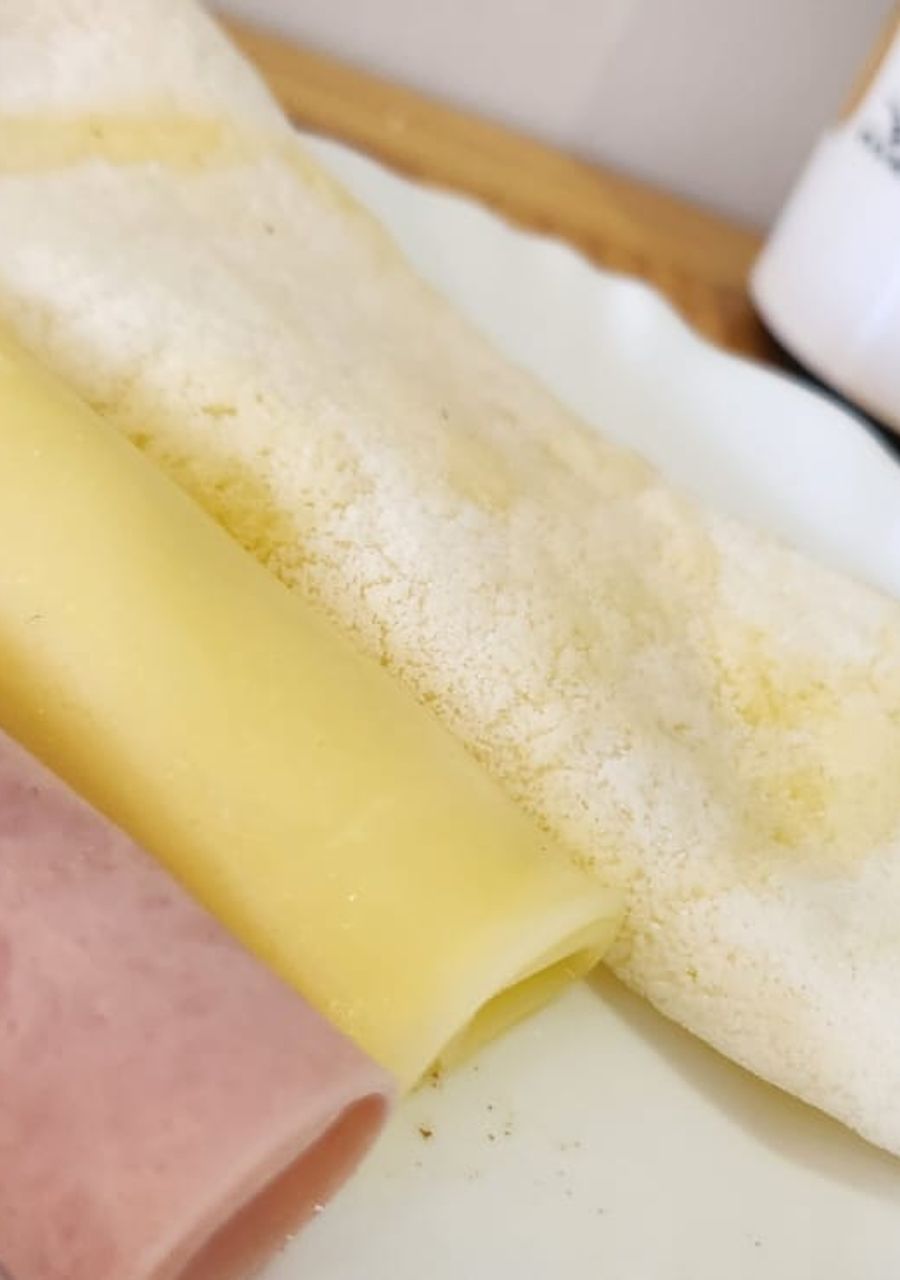 A rolled-up item with a yellow and pink section, possibly a food item, on a white surface.