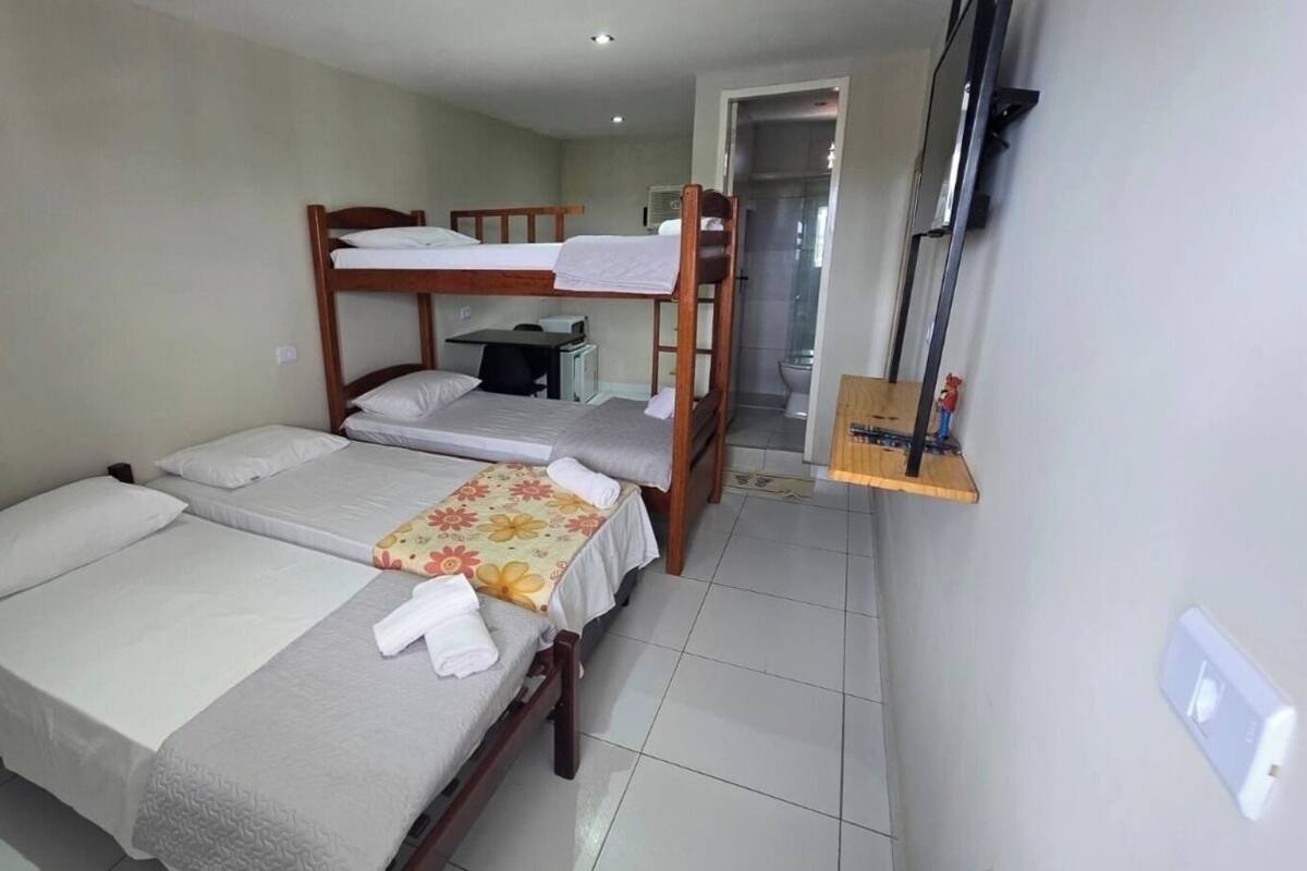 A hotel room with two single beds, a small desk, and a shower area.