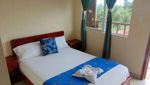 A neatly made bed with a blue and white bedspread, a white pillow, and a blue pillow with a floral pattern. - MIRAMAR LODGE  (Pedernales)