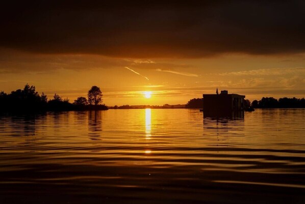 A sunset over a calm body of water with a building on the right.
