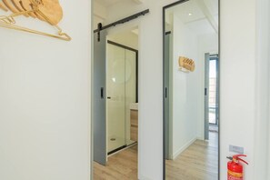 A modern interior with a sliding glass door leading to a room with a wooden floor and a glass partition.