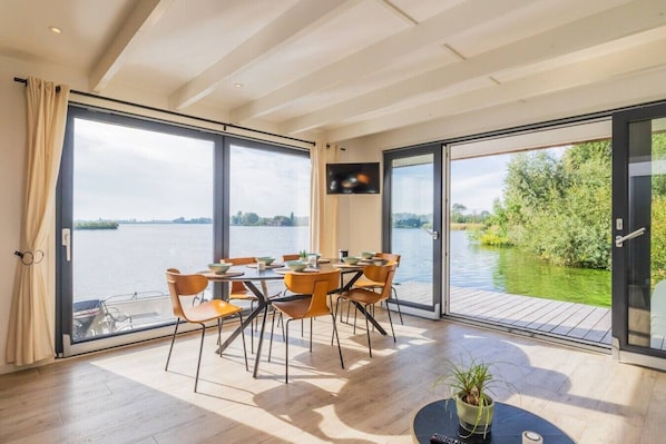 A dining area with a table and chairs, large windows, and a view of a body of water.