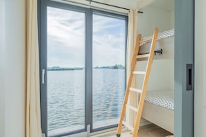 Habitación con vista a un cuerpo de agua, una cama individual y una escalera.
