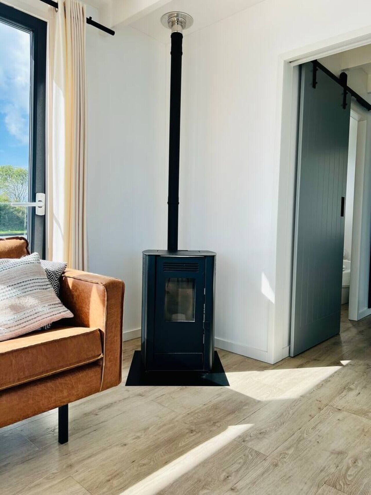 Een kamer met een moderne haard, een bank en een deur naar een andere ruimte.