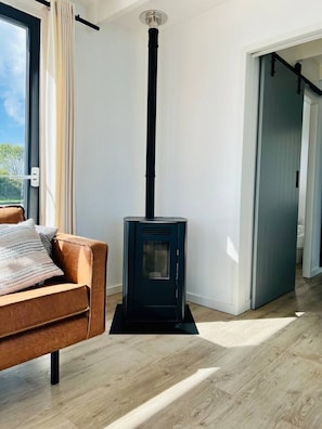 A room with a modern fireplace, a sofa, and a door leading to another area.