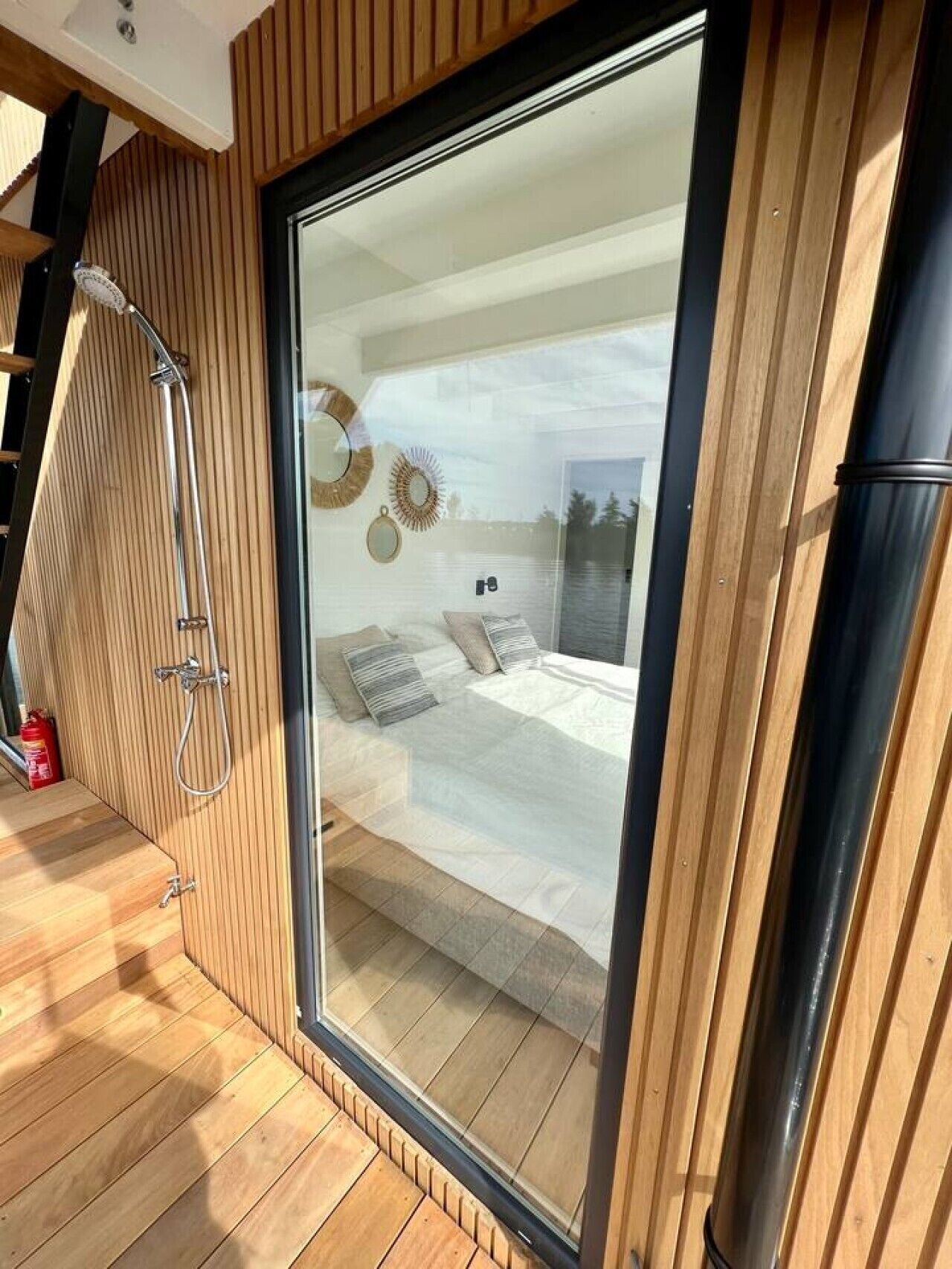 Ein modernes Schlafzimmer mit einer großen Schiebeglaswand, einer Duschkabine und einem Bett mit Kissen.
