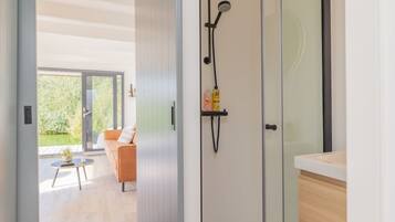 Een moderne badkamer met een glazen douchecabine, een handdoekrek met toiletartikelen en een uitzicht op een terras.