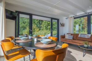 Una sala de estar moderna con una mesa de comedor redonda, sillas amarillas y un sofá marrón.