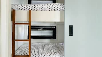 Een stapelbed met een ladder, een raam met zonwering en een deur.