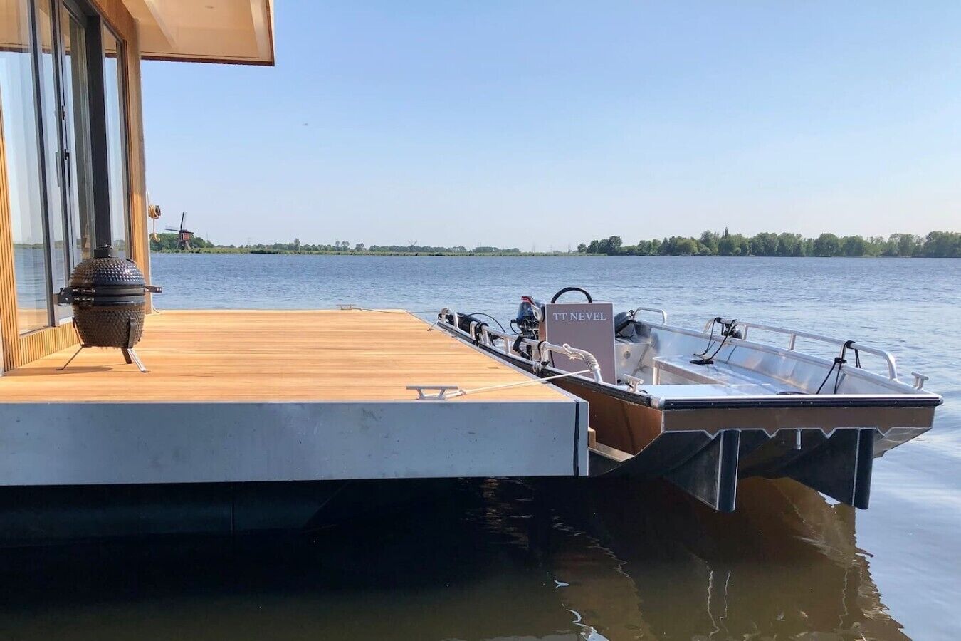 A boat docked at a wooden pier with a grill and a sign reading 'TT NEVEL'.