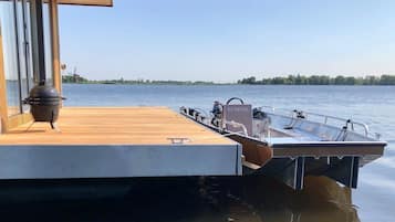 Een boot afgemeerd aan een houten steiger, met een barbecue en een bord waarop 'TT NEVEL' staat.