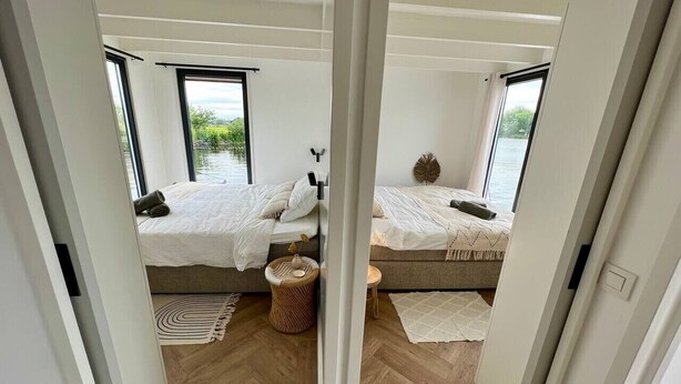 A bedroom with two beds, a window, and a view of the outdoors.