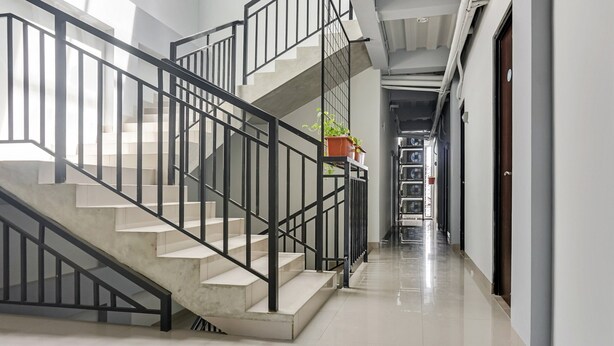 Eine moderne Treppe mit schwarzen Geländern und einem Blumentopf auf der Landung.