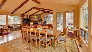 A spacious dining area with a large wooden table and chairs, a stone fireplace, and a television. - 2 Mi to River Run Day Lodge: Family-Friendly Home (Sun Valley)