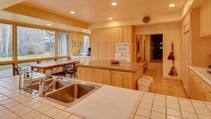 A modern kitchen with wooden cabinets, a granite countertop, and a large window overlooking a garden. - 2 Mi to River Run Day Lodge: Family-Friendly Home (Sun Valley)