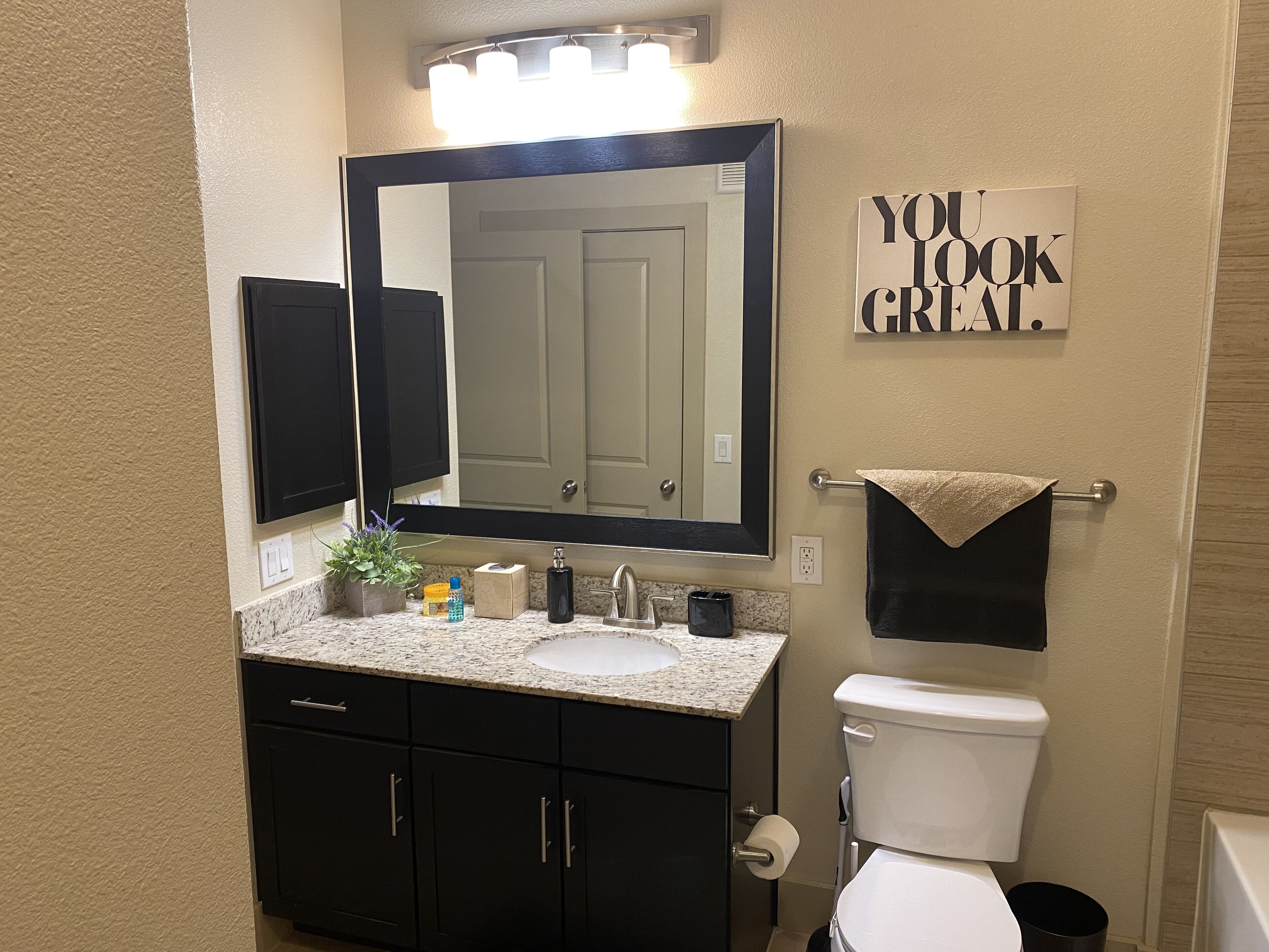 Une salle de bain équipée d’un lavabo, d’un miroir, de toilettes et d’un porte-serviettes.