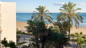 A beach view with palm trees and a clear sky.