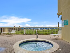 Ein Poolbereich mit Whirlpool, Liegestühlen und Blick auf den Strand.