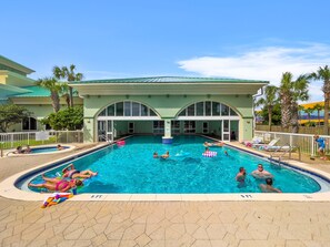 A swimming pool with multiple lanes, palm trees, and a building with arched windows.