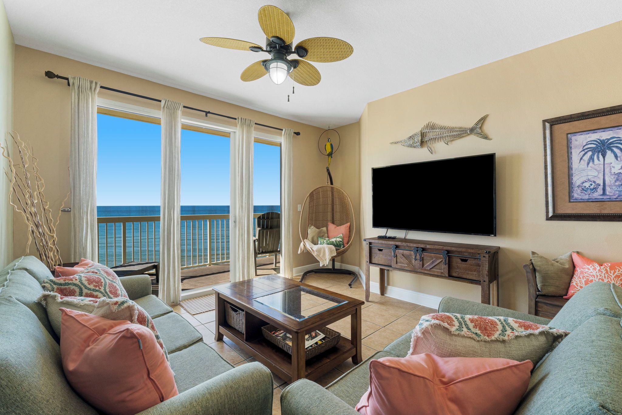 A living room with a large window, a ceiling fan, a flat-screen TV, and a wooden cabinet.