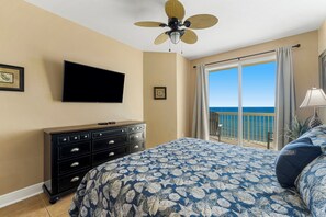 Une chambre avec un lit, une commode, une télévision et un balcon donnant sur l’océan.