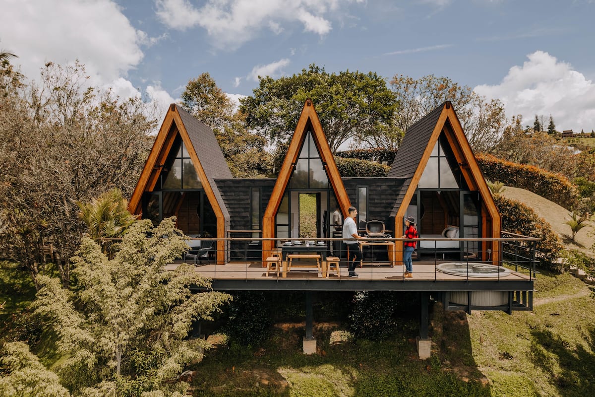 A modern house with a wooden deck, large windows, and a dining area.