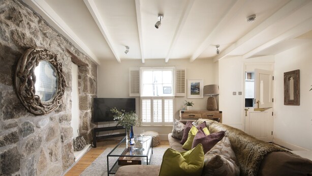 Un salon chaleureux avec un mur en pierre, un téléviseur, un canapé avec des coussins et une table basse en bois.