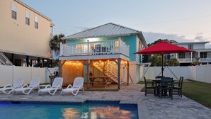 A pool area with lounge chairs, a dining table, and a covered deck with string lights. - Rocks On The Side: Private Pool, Steps to the Beach, Murrells Inlet (Murrells Inlet)