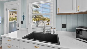 A modern kitchen with a black sink, white cabinets, and a window with blinds. - Rocks On The Side: Private Pool, Steps to the Beach, Murrells Inlet (Murrells Inlet)