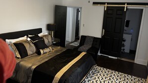 Ein Schlafzimmer mit Bett, Stuhl, Deckenventilator und Tür.